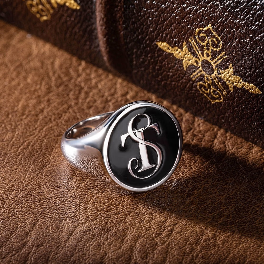 Custom silver initial signet ring displayed on brown leather