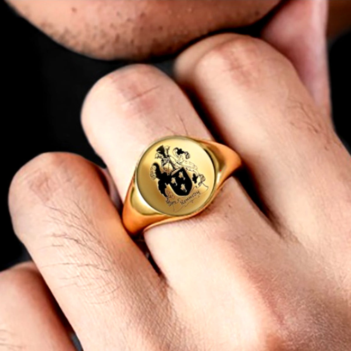 Gold-tone personalized family crest signet ring worn on a man's finger