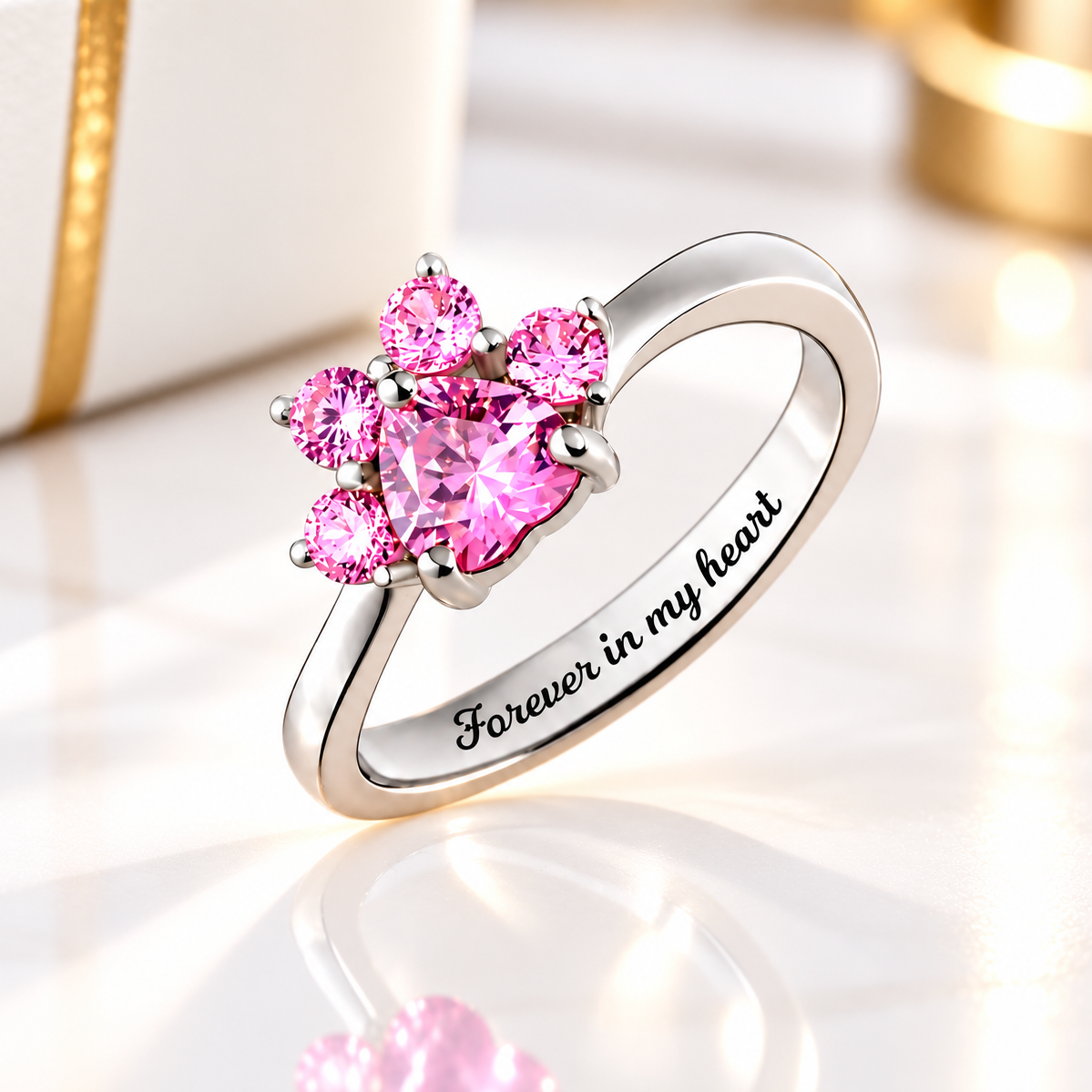 Pink cubic zirconia paw print birthstone ring in 925 sterling silver with Forever in my heart engraving, displayed on black leather.