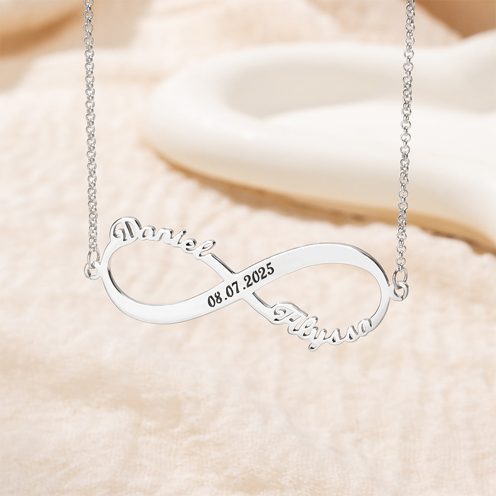 Personalized silver two name infinity necklace displayed on cream fabric