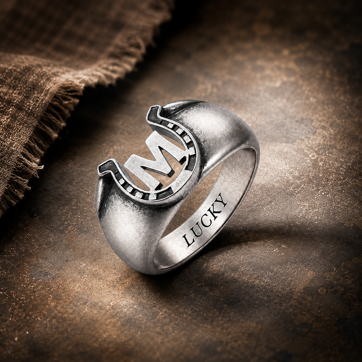 Personalized M initial horseshoe ring with LUCKY engraving on rustic dark background
