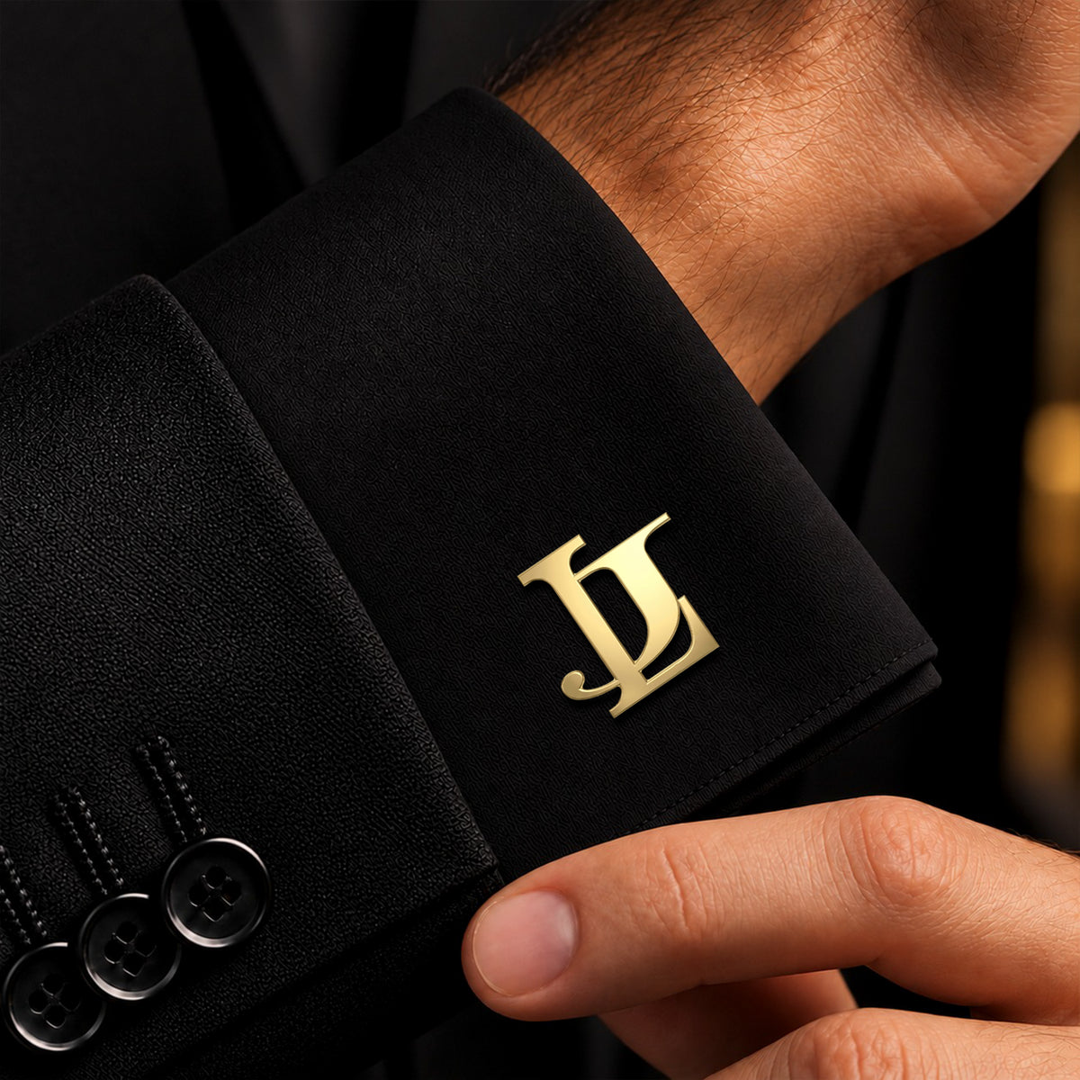Close-up of personalized gold entwined initials cufflink on a black dress shirt cuff.