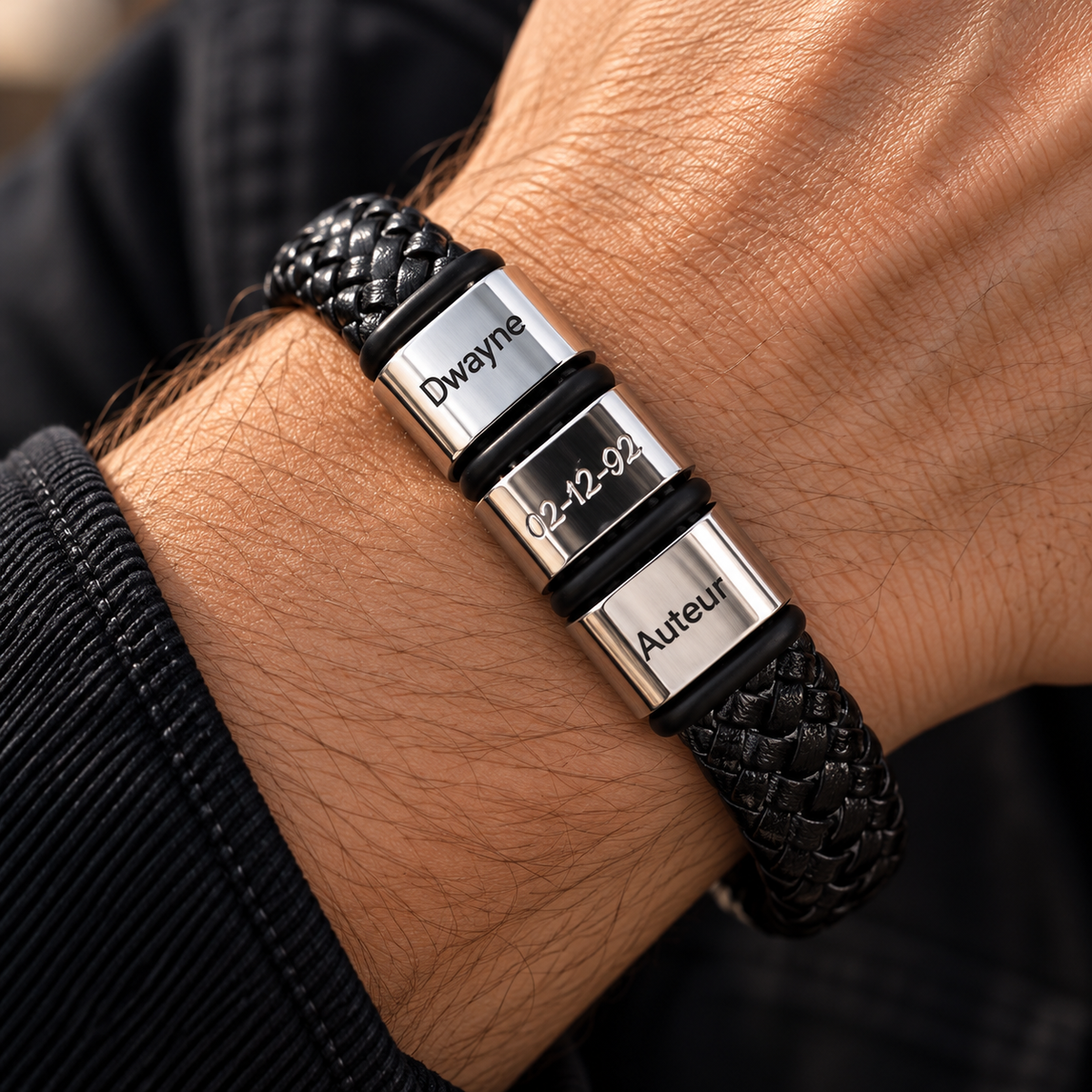 Close-up of a men's personalized black braided leather bracelet worn on the wrist, featuring custom engraved family names and a heart charm. A meaningful Father's Day gift for Dad or husband.