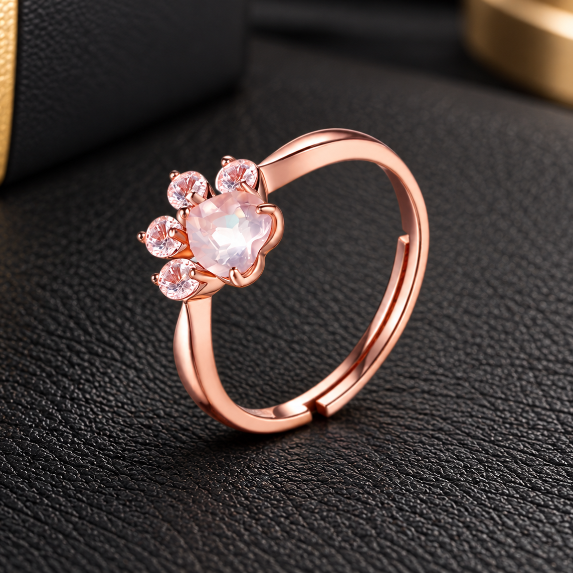 Natural Crystal Pink Cat Paw Ring in rose gold tone, featuring a delicate pink crystal paw print design and adjustable band on black leather.