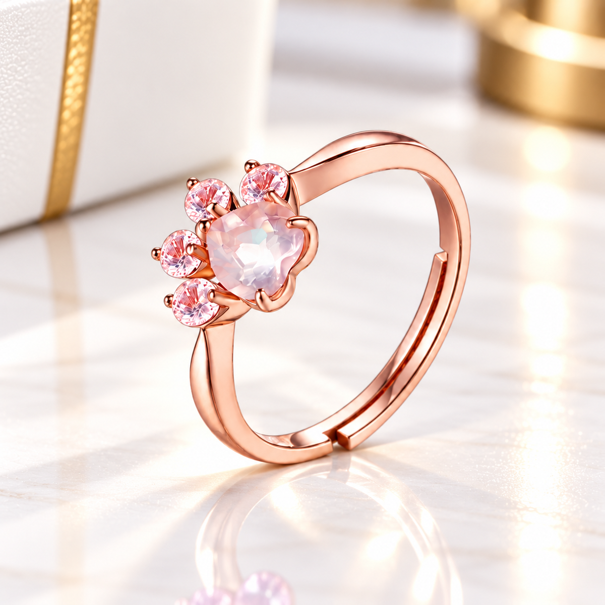 Natural pink crystal cat paw ring in rose gold, featuring a heart-shaped pale pink gemstone and four sparkling pink stones, displayed on an elegant white and gold background.