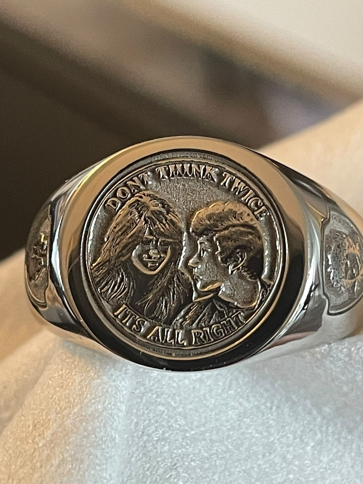 Side-angle view of a bespoke portrait signet ring with detailed couple engraving and decorative shield emblem.