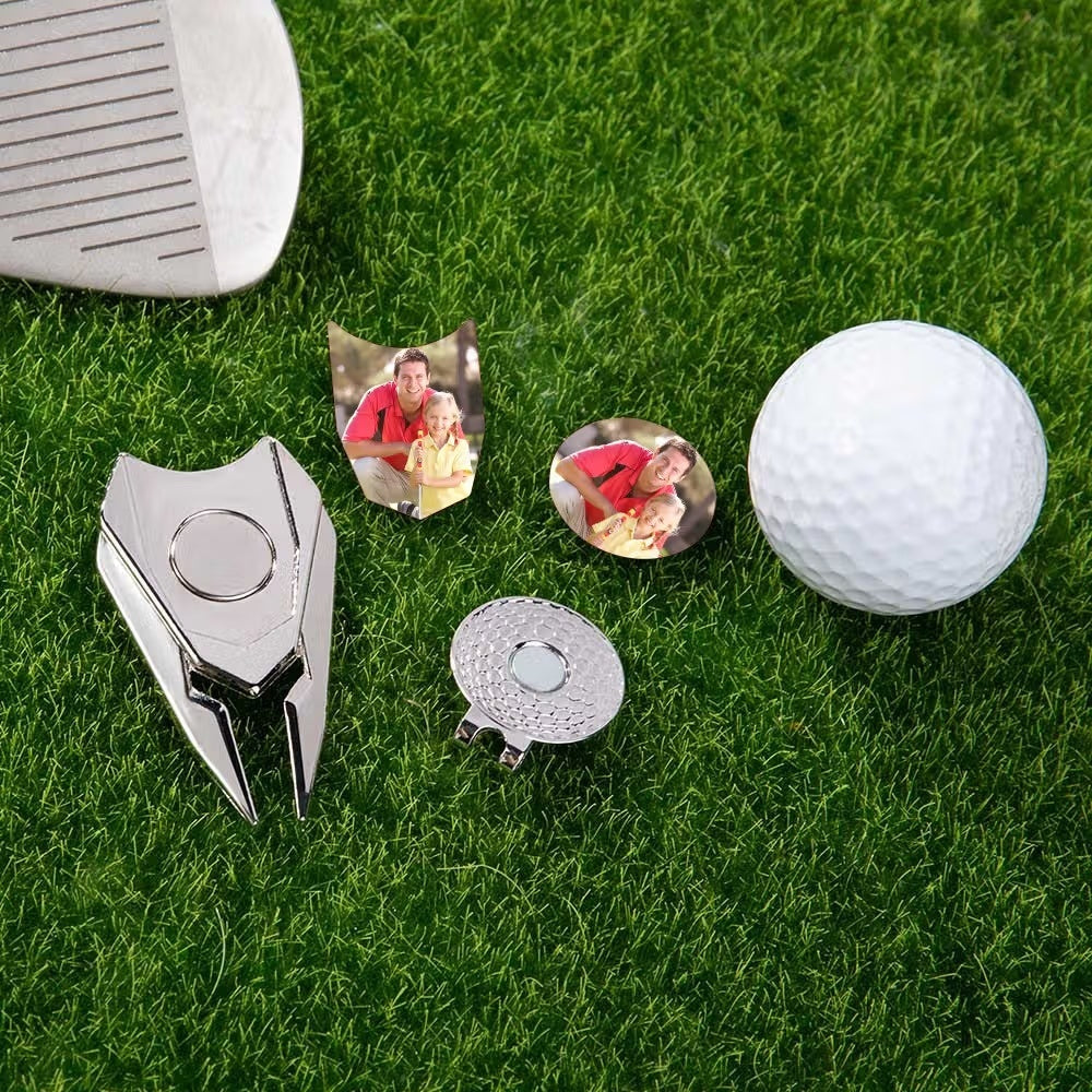 Custom golf divot tools and personalized photo ball markers displayed on grass with golf ball