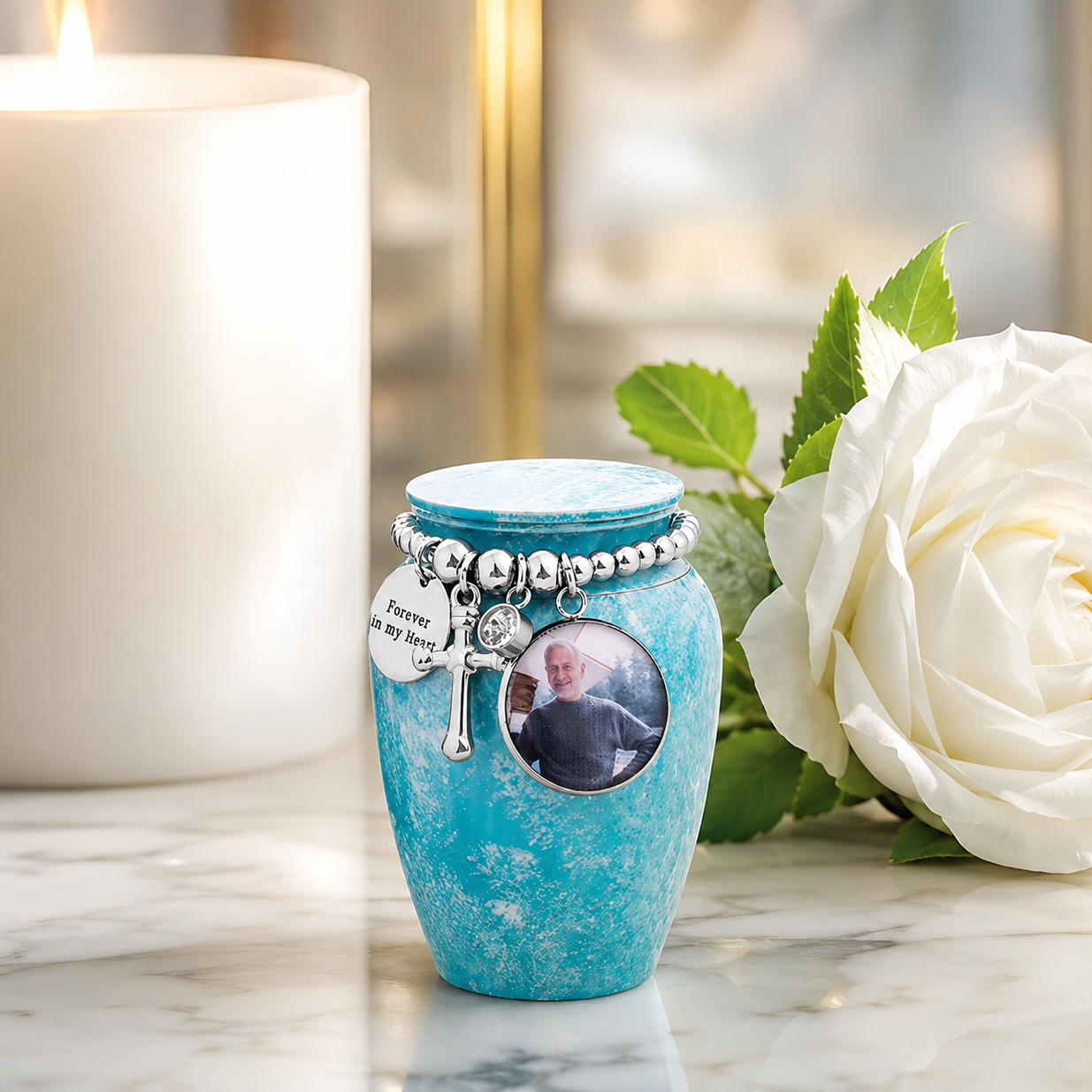 Personalised mini cremation urn with photo engraving displayed beside a white rose and candle for remembrance.