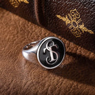 Custom silver initial signet ring displayed on brown leather