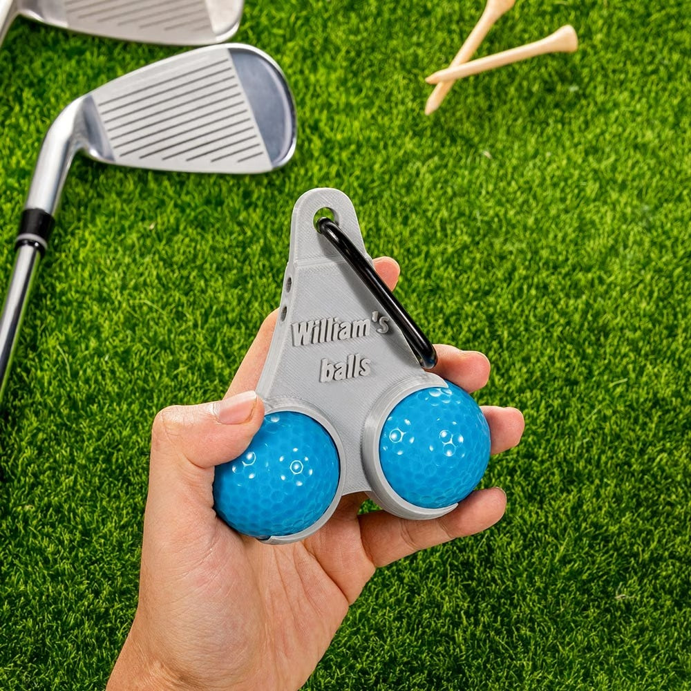 Personalized golf ball and tee holder held by hand on golf course grass