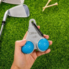 Personalized golf ball and tee holder held by hand on golf course grass
