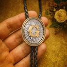 Personalized bolo tie with gold letter G, engraved design, and braided cord, perfect custom gift for special occasions.