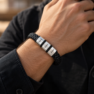 Close-up of a man's wrist wearing a black braided bracelet with three silver-tone engraved beads, a personalized gift for Dad.