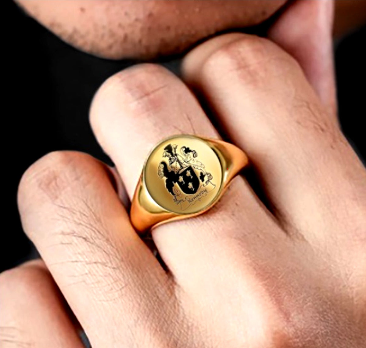 Gold-tone personalized family crest signet ring worn on a man's finger