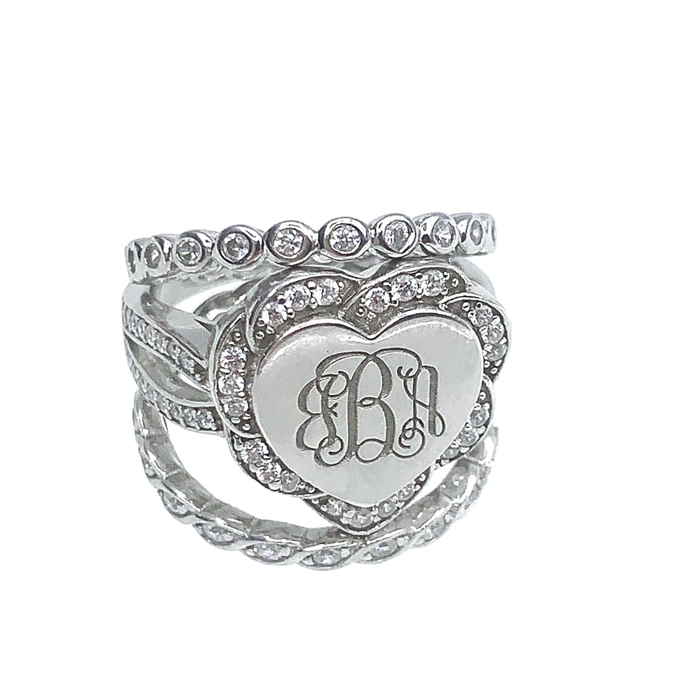 A heart-shaped sterling silver stackable ring with "JBA" monogram, encrusted with cubic zirconias on a twisted band design.