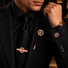 Man wearing rose gold geometric monogram cufflinks, matching tie bar and lapel pin with a black suit