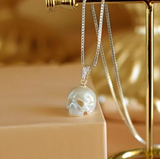 Iridescent skull pendant on a sterling silver chain, elegantly suspended against a soft beige backdrop.