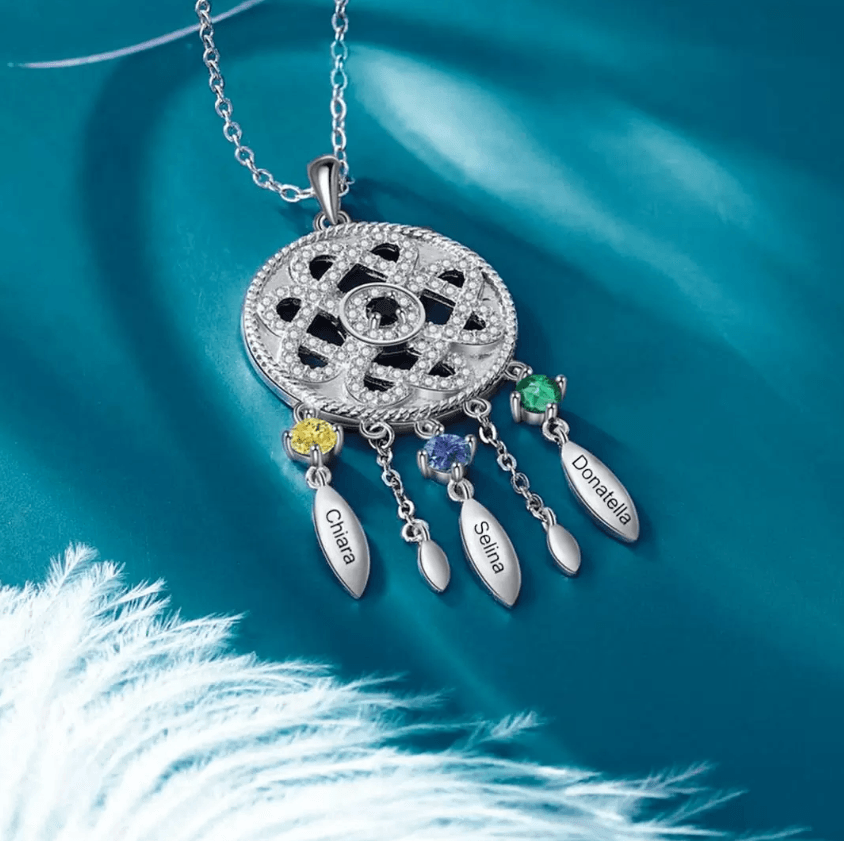 Intricate silver pendant with colorful gemstones and name tags for Chiara, Selina, Daniella on teal silk.