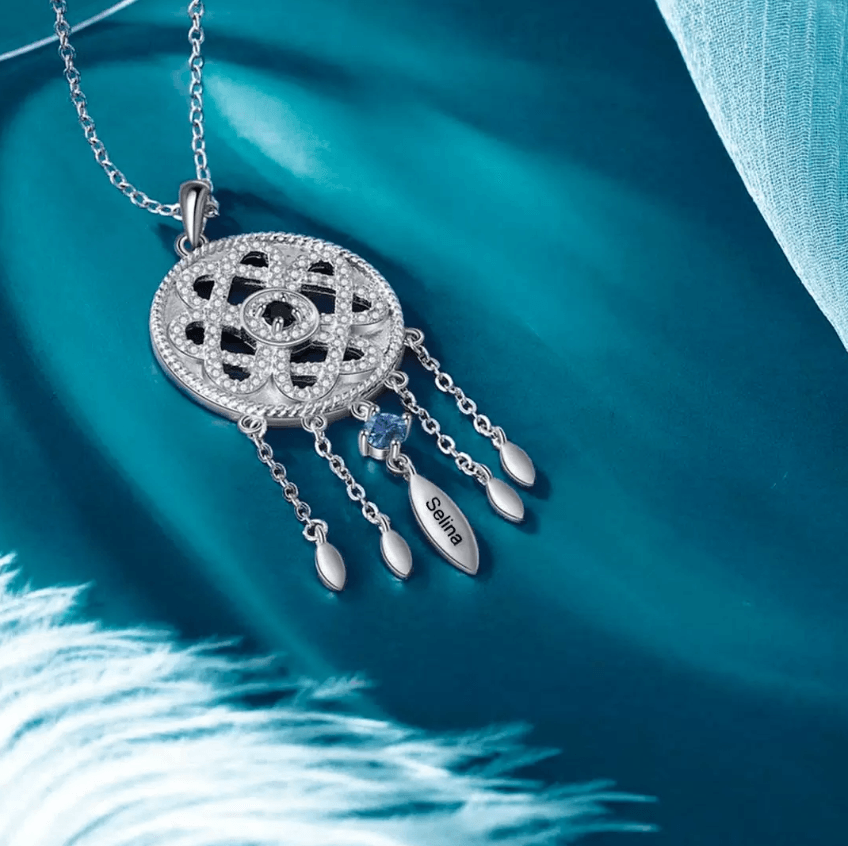 Silver pendant with intricate design and blue gem, on a teal silk background, named 'Selina'.