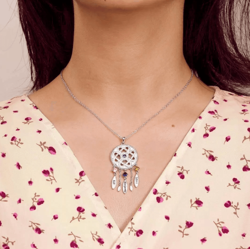 Woman wearing a silver filigree pendant necklace with colorful gems on a floral dress.