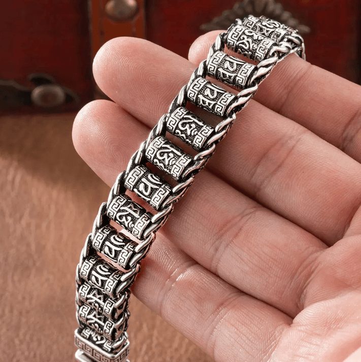 Close-up of a hand holding a detailed silver geometric patterned bracelet, highlighting its exquisite craftsmanship.