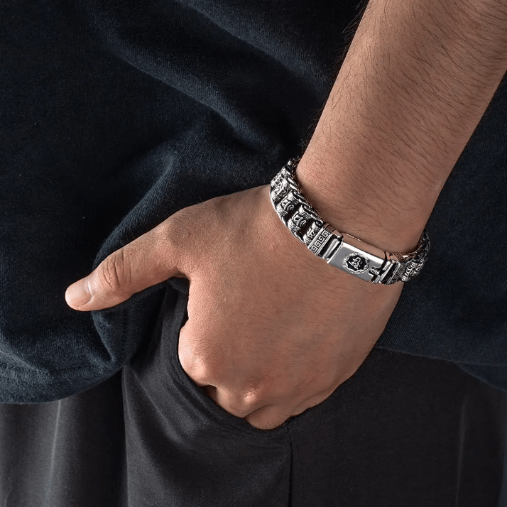 Man wearing a Tibetan Om Mani Padme Hum spinner bracelet, showing detailed silver design on a black shirt