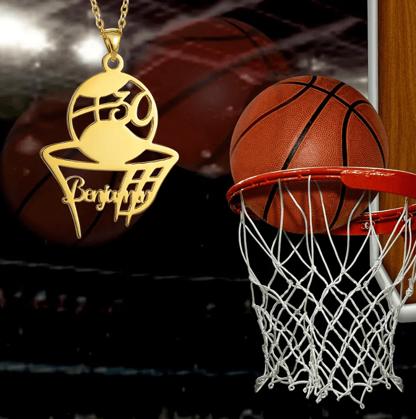 Gold basketball pendant necklace with 'Bryant #30' engraving, displayed beside a basketball hoop in a dimly lit gym.