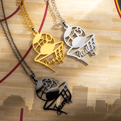 Gold, silver, and black basketball pendant necklaces with player names and numbers displayed on a wooden court background.