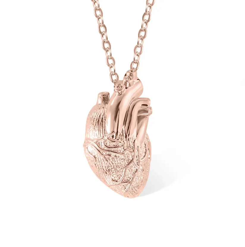 Rose gold anatomical heart pendant on a chain, with a detailed texture, isolated on a white background.