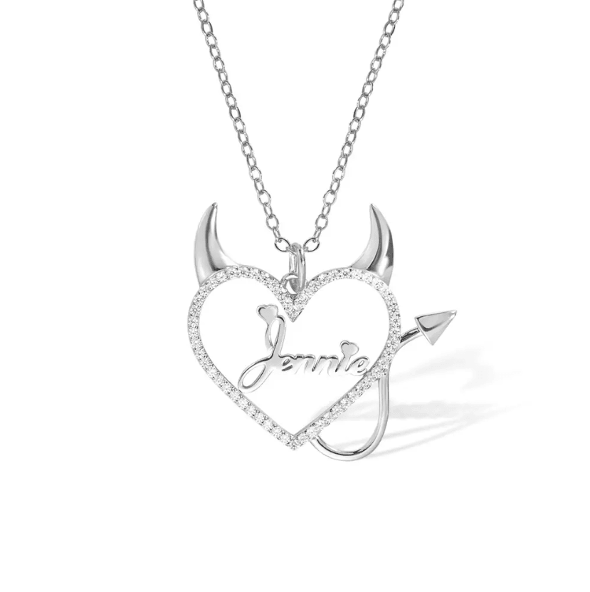 Silver necklace with a heart-shaped pendant featuring devil horns and tail, with the name "Jennie" in the center and surrounded by sparkling stones, displayed on a white background.