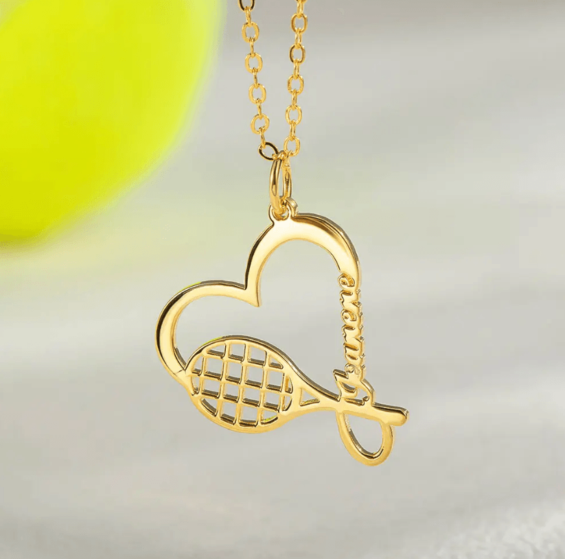 Gold tennis racket necklace with a heart charm, customized with the name "Janene." Ideal sports jewelry gift for tennis enthusiasts and athletes.