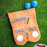 Custom tan flannelette golf ball sack labeled 'Kayden's Ball Sack' on grass, with golf balls, tees, showcasing a humorous and personalized design.