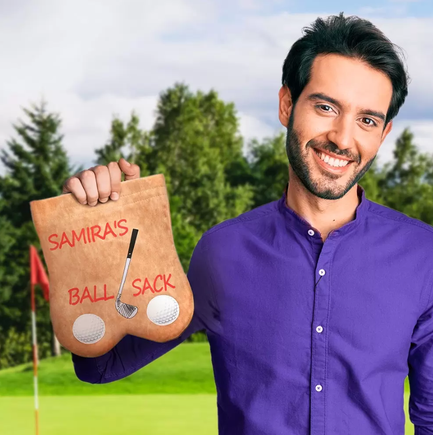 Smiling man in a purple shirt holding a personalized 'Samira's Ball Sack' golf accessory, with a golf course backdrop, highlighting a custom, fun gift.