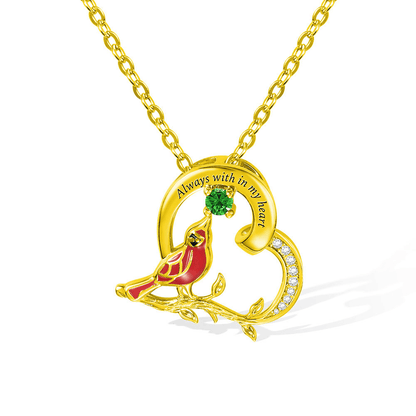 Gold cardinal pendant with 'Always with in my Heart' engraving and green gemstone on a gold chain.