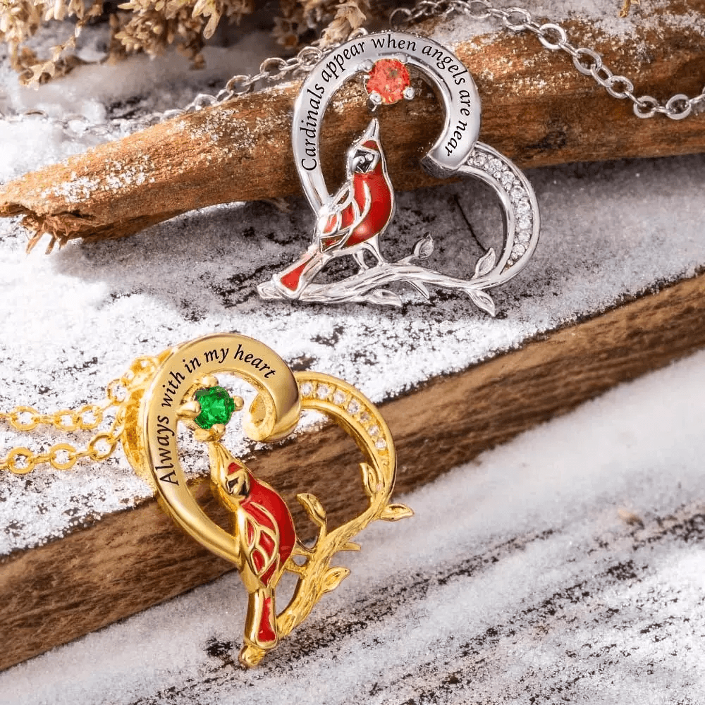 Memorial cardinal necklaces in silver and gold on snowy branch, with engravings and gemstones.
