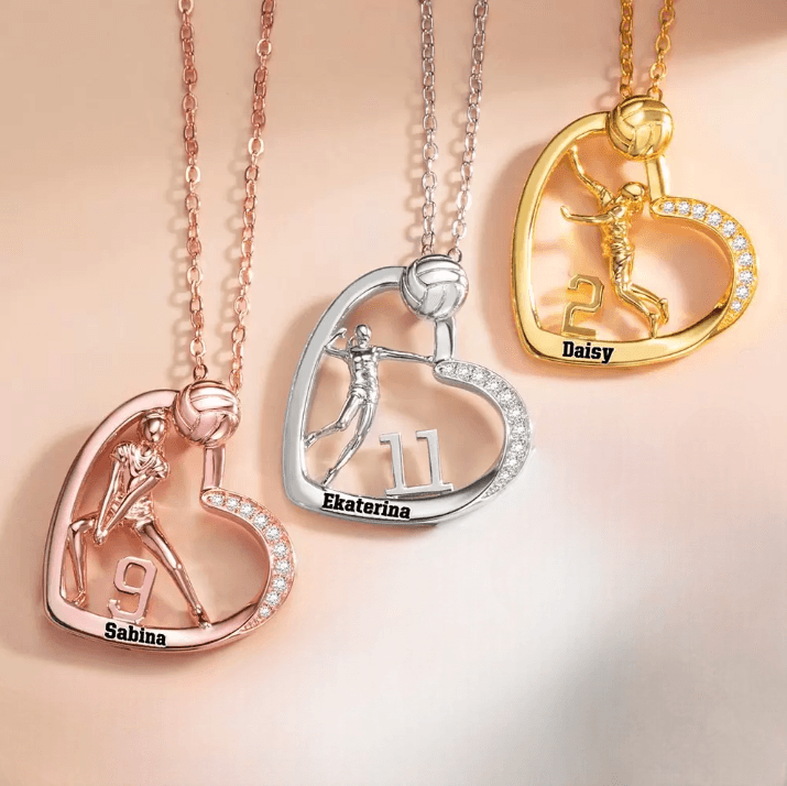 Three heart-shaped volleyball-themed necklaces in rose gold, silver, and gold, each with a player's figure, number, and name: Sabina (9), Ekaterina (11), Daisy (2).