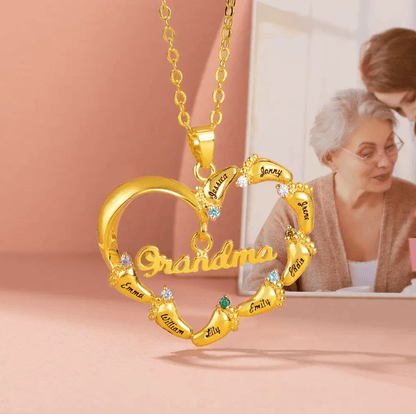A heart-shaped gold necklace for "Grandma" with names and colorful gemstones. A loving elderly woman in the background reads with her granddaughter.