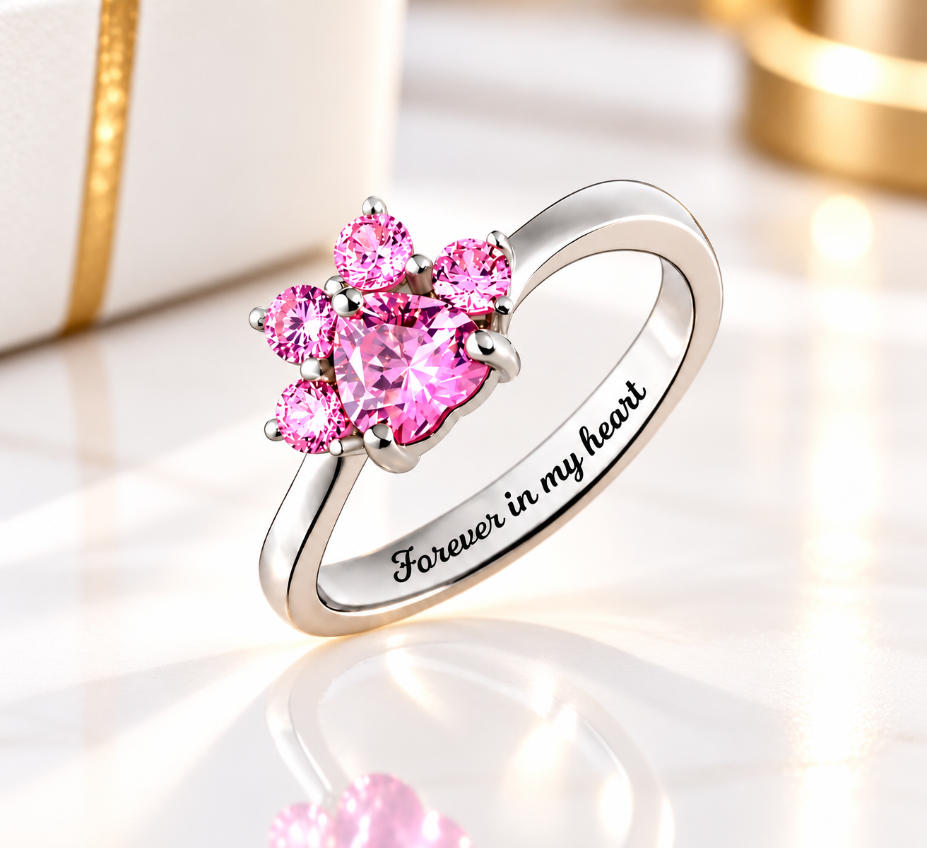 Pink cubic zirconia paw print birthstone ring in 925 sterling silver with Forever in my heart engraving, displayed on black leather.