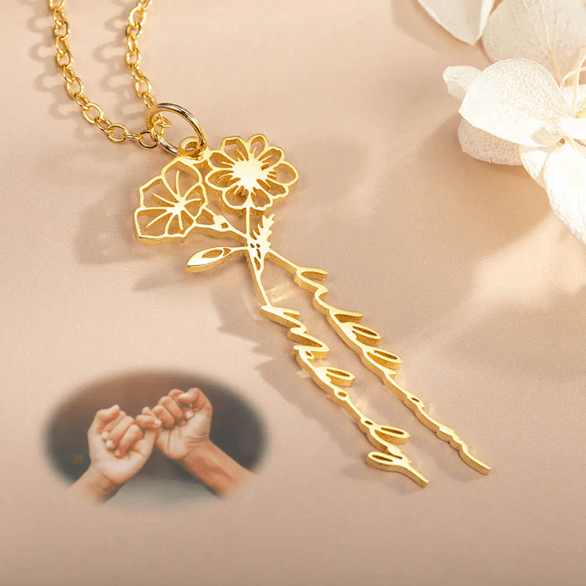 Gold Personalized Birth Flower Necklace with custom names, displayed on a beige surface with white flowers, featuring a small image of two hands making a pinky promise.