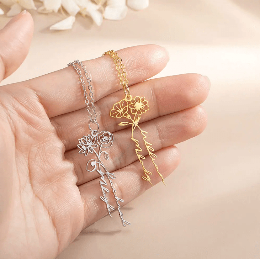 Hand holding two Personalized Birth Flower Necklaces with custom names, crafted in sterling silver and gold, showcasing delicate and elegant design.