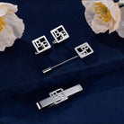 Personalized silver square initial cufflinks with matching tie bar and lapel pin on navy blue fabric