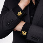 Gold interlocking initials cufflinks worn with a dark grey blazer and black shirt