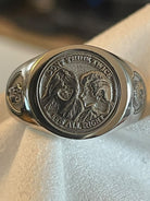 Close-up of a custom portrait signet ring featuring two engraved faces and a polished metal band.