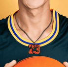 A person wearing a basketball-themed pendant with the number "23" and the name "Mason" engraved on it, holding a basketball while dressed in a jersey.