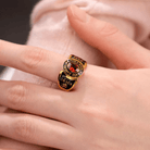 A gold college ring with a red gemstone, inscribed with "COLLEGE LOS ANGELES," "2024," and "GRACE" with an Om symbol, worn on a person's hand.