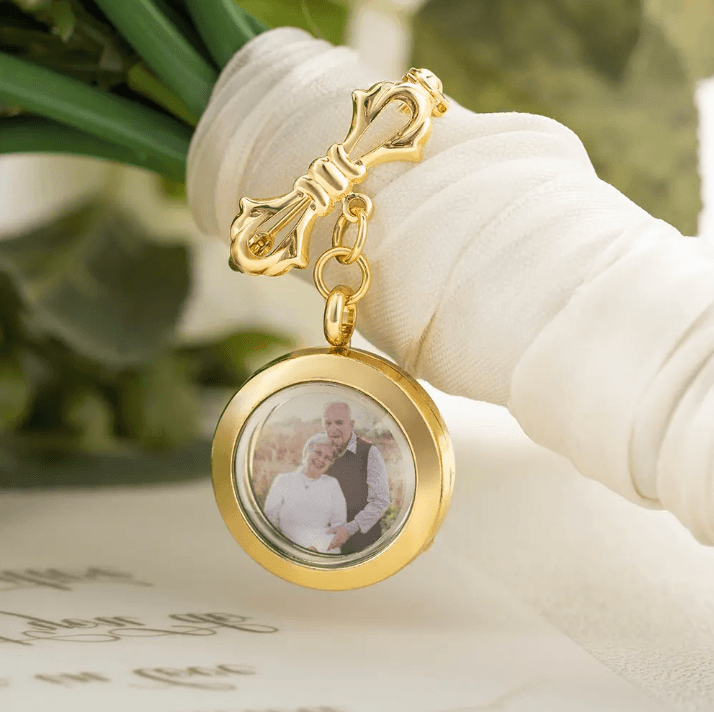 A bridal bouquet adorned with a golden photo pendant, featuring an image of a couple.