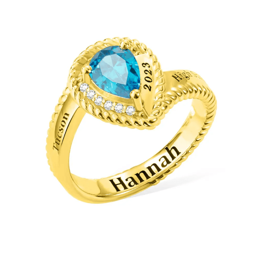 Gold class ring with blue heart-shaped gem, '2023, High, Hannah' engraved for custom graduation jewelry.