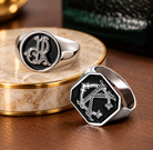Two custom double initials signet rings in polished silver tone with black faces and intertwined monogram designs.