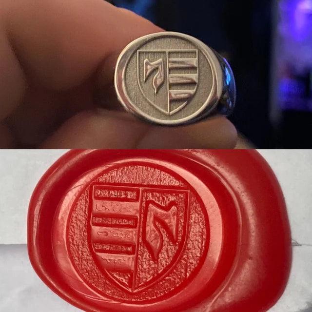 Silver signet ring with crest and red wax seal impression, held between fingers for sealing.