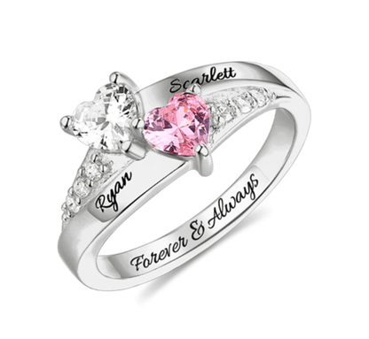 A silver ring with two heart-shaped gemstones, one clear and one pink, personalized with the names Ryan and Scarlett, and the inscription "Forever & Always."